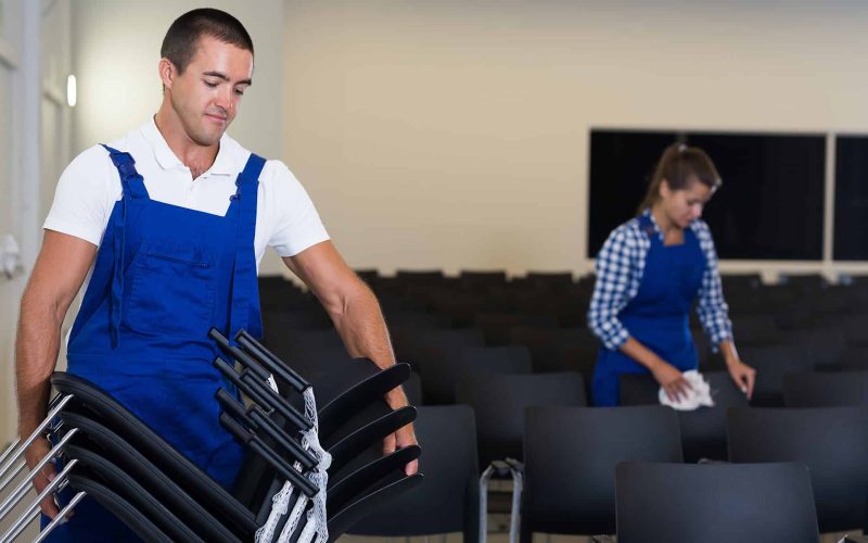 Man and woman in overalls preparing conference hall for event