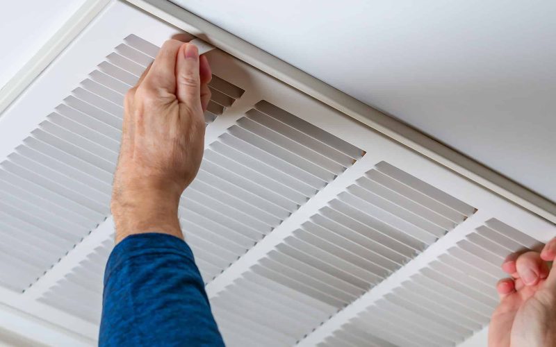 Man opening ceiling air vent to replace dirty HVAC air filter. H